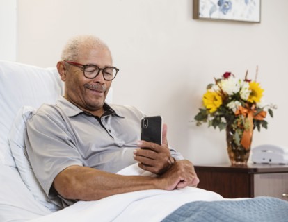 Senior man lying in bed and using smart phone