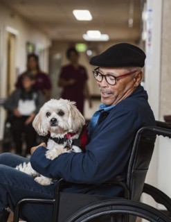 Senior man in wheelchair holding service dog