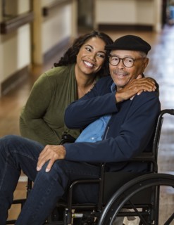 Daughter embracing senior father in wheelchair