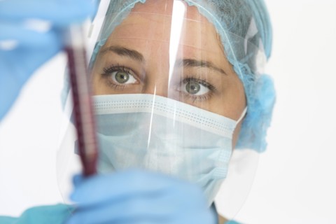 Nurse in mask and face shield holding blood sample