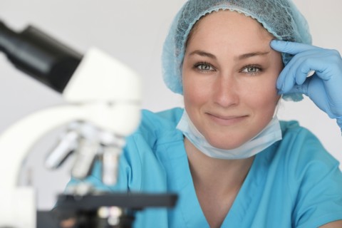 Portrait of laboratory technician next to microscope