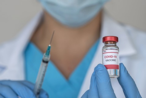 Close-up of doctors hands holding Covid-19 vaccine and syringe