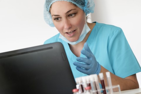 Woman in protective lab workwear sitting in front of laptop