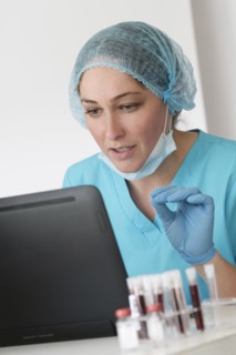 Woman in protective lab workwear sitting in front of laptop