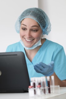Woman in protective lab workwear sitting in front of laptop
