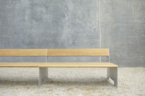 Wooden modern bench against concrete wall