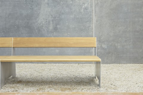 Wooden modern bench against concrete wall