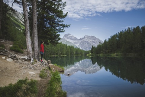 Switzerland, Bravuogn, Palpuognasee, Young woman resting on bench near Palpuognasee lake in Swiss Alps