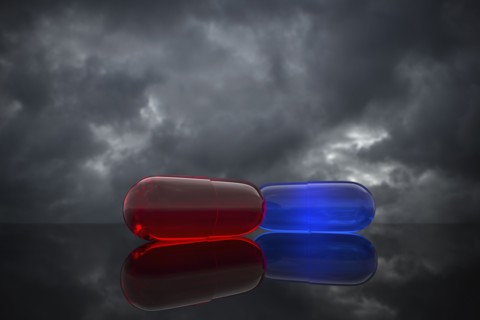 Red and blue pills on cloudy background