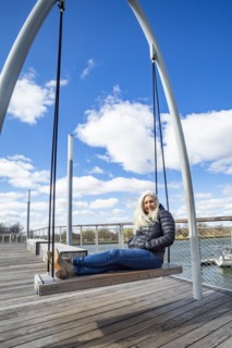 USA, Washington D.C., Senior woman on swing at Wharf District along Potomac River