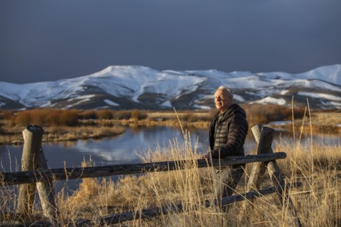 USA, Idaho, Sun Valley, Senior man leaning against fence looking at view