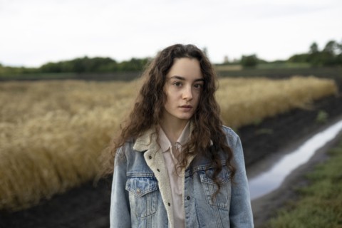 Russia, Omsk, Portrait of young woman with brown hair standing in field