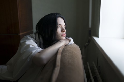 Young woman looking through window
