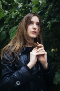 Portrait of young woman standing by tree