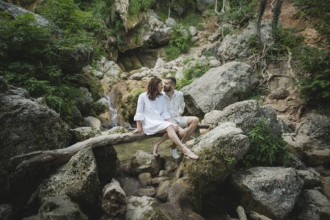 Ukraine, Crimea, Young couple sitting on branch over river in canyon
