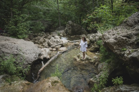 Ukraine, Crimea, Young woman standing on rock in river
