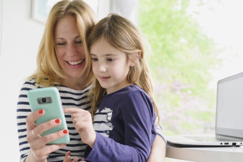 Mother and daughter (6-7) using smart phone