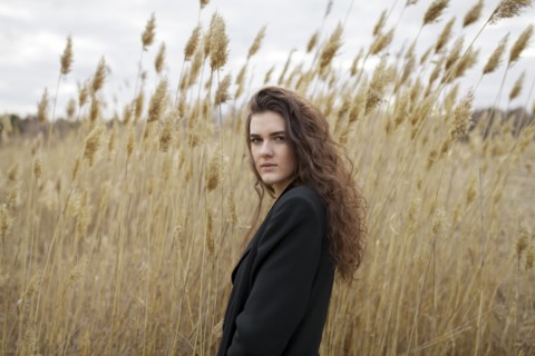 Russia, Omsk, Portrait of young woman in tall grass