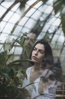 Ukraine, Crimea, Young woman looking at plant in greenhouse