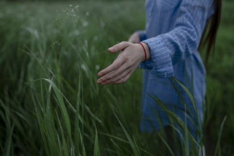 Russia, Omsk, Mid section of woman in tall grass