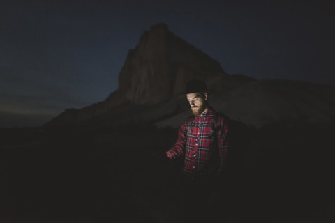 Ukraine, Crimea, Man in hat with glowing phone standing near White Mountain at night