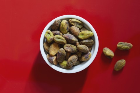 Pistachios in bowl on red background