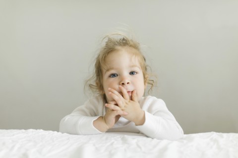 Portrait of toddler girl leaning on bed