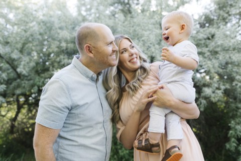 Happy parents with baby son laughing in garden