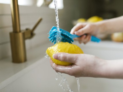 Woman washing lemon with brush