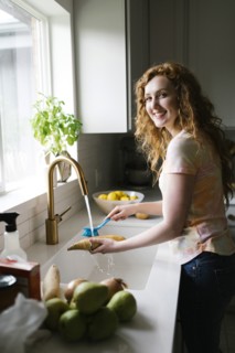 Woman washing sweet potato with brush
