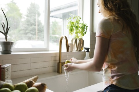 Woman washing pear in kitchen