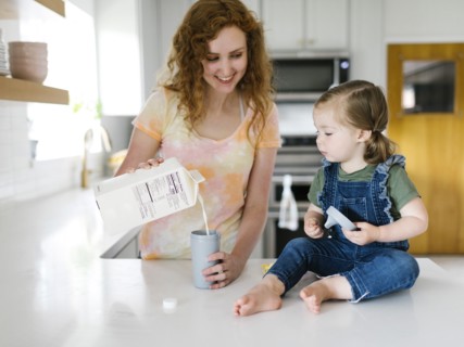 Mother pouring milk for daughter (2-3)