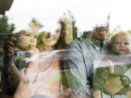 Family with children (6-11 months, 2-3) looking through window,