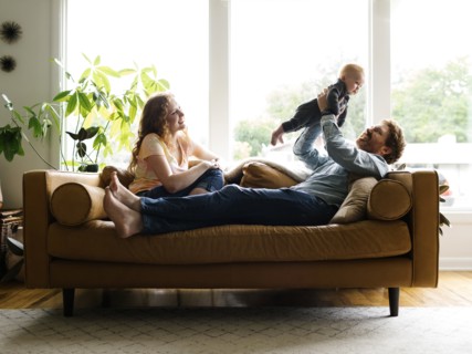 Mother and father playing with baby son (6-11 months) on sofa