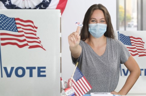 Woman in face mask holding voting sticker