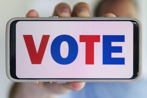 Hand holding smartphone with voting message