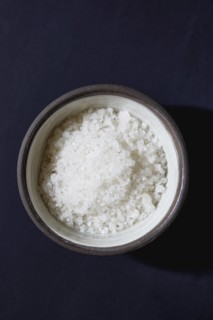 Sea salt in bowl on blue background