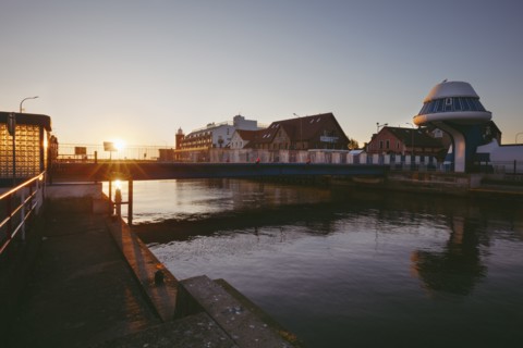 Poland, West Pomerania, Darlowek, Lighthouse and bridge over Wieprza River at sunset