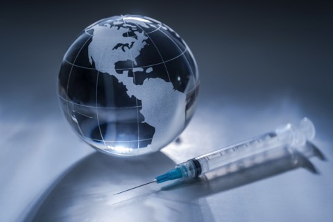 Glass globe and syringe on gray background