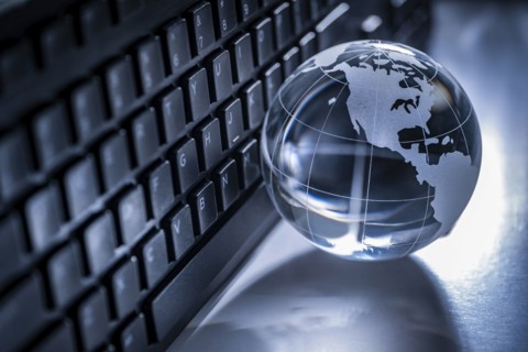 Glass globe and computer keyboard on gray background
