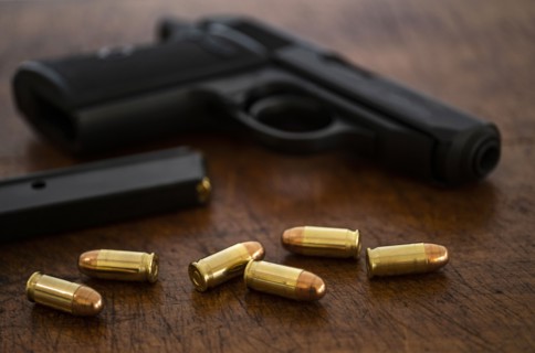 Gold bullets and pistol on wooden surface