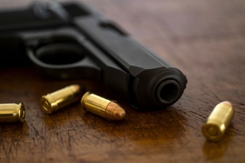 Gold bullets and pistol on wooden surface