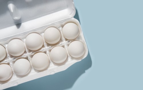Eggs in carton on blue background