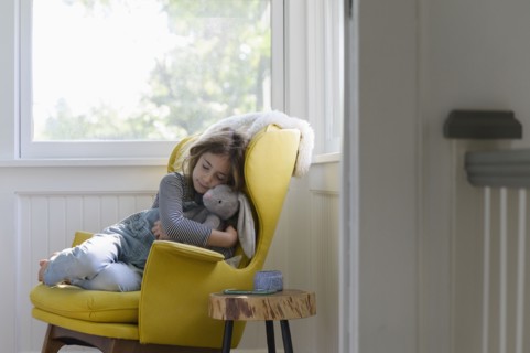 Girl (5-7) relaxing in armchair