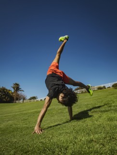 Man doing cartwheel on grass