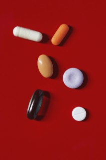 Various pills and capsules on red background