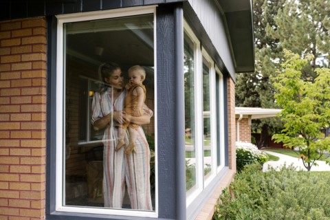 Mother with baby son (18-23 months) standing behind window