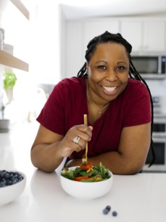 Portrait of smiling woman having healthy salad in kitchen