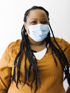 Studio portrait of woman wearing protective face mask and orange dress
