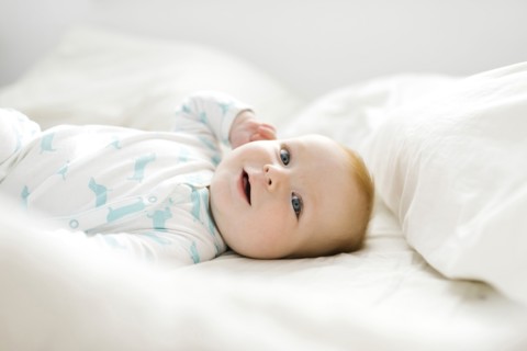 Baby boy (6-11 months) lying on bed